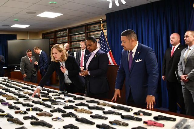 Queens District Attorney Melinda Katz and New York City Police Commissioner Keechant L. Sewell examine guns seized in the multi-state trafficking ring.